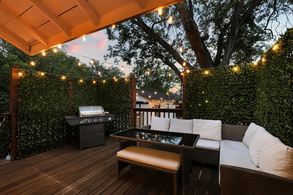 Longhorn outdoor deck at dusk with string lights, sectional seating, and gas grill